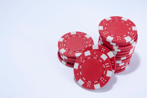 Red poker chips stacked on a white background with space for text