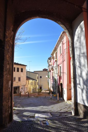A vertical shot of a narrow street amid colorful residential buildings in Campobasso, Italy