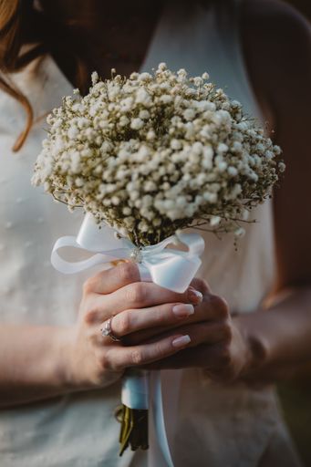 A closeup of the bride's hands holding her wedding bouquet with gypsophila flowers