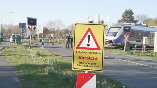 A selective focus shot of a German warning sign warning of the railroad crossing