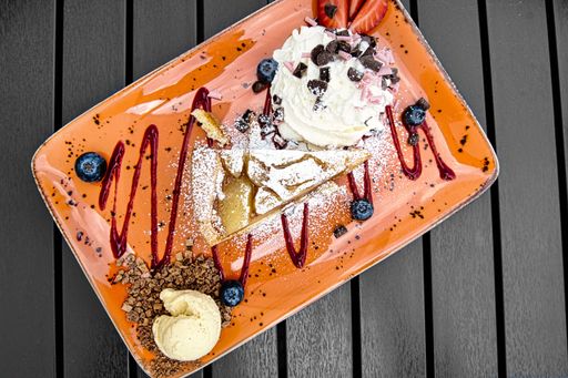a top view shot of desert on plate with cream and chocolate