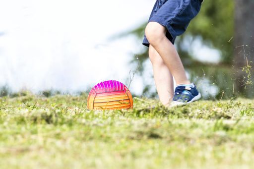 A closeup shot of a child playing ball in the garden