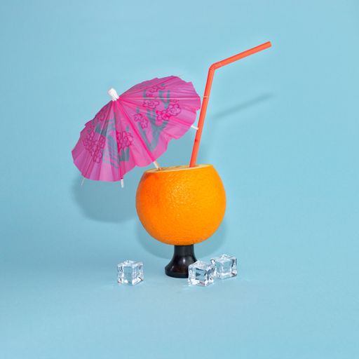 A closeup of an orange with a straw on a blue background as a concept of party and relax