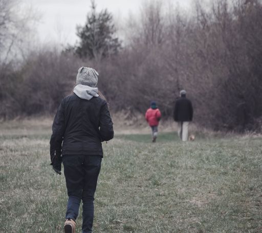 A rear view of a woman walking on a field with two-person in front of her