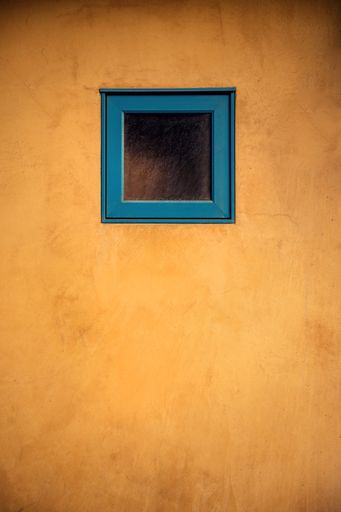 A vertical shot of a tiny blue window on a wooden door