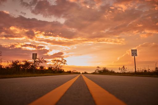 A scenic view of the road in the Florida Everglades National Park at sunset under the cloudy sky