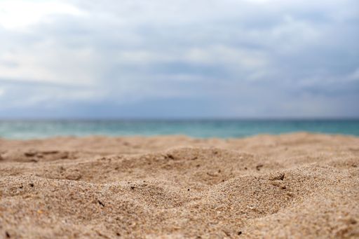 A selective focus low angle view of the sandy beach under the cloudy sky in Florida before sunset