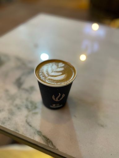 A vertical shot of a coffee in a plastic cup with designed foam on top