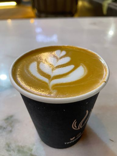 A vertical shot of a coffee in a plastic cup with latte art on top