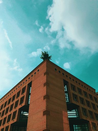 A vertical low angle shot of a concrete building under the beautiful cloudy sky