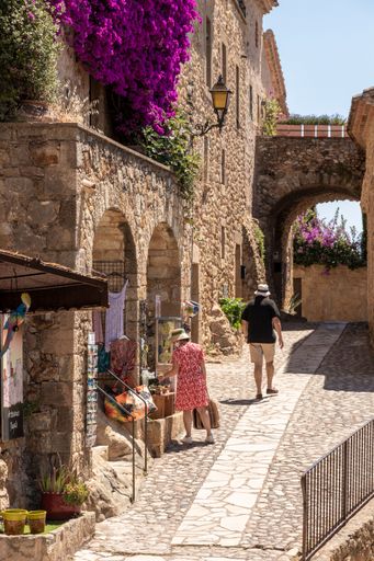 A tourist couple walking through the medieval streets of Pals on the Costa Brava on a sunny summer day