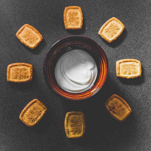 A high angle shot of beautifully decorated cookies and a bowl of sour cream on a grey surface
