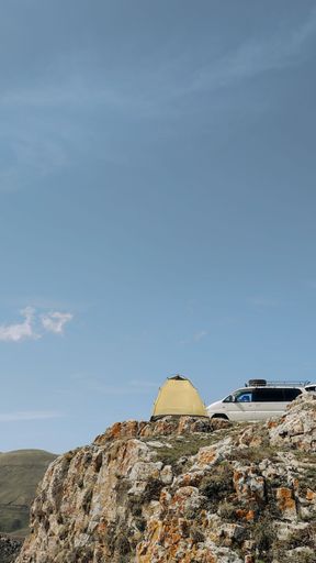 A beautiful view of tent and car on a cliff under the clear sky