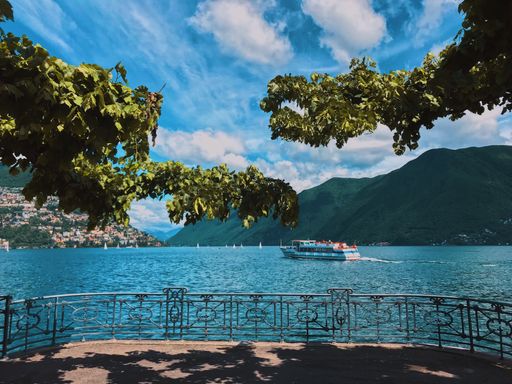 A horizontal shot of a cruise ship on the sea surrounded by beautiful green mountains under the cloudy sky