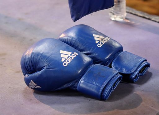 A closeup shot of a pair of blue Adidas boxing gloves in a rink