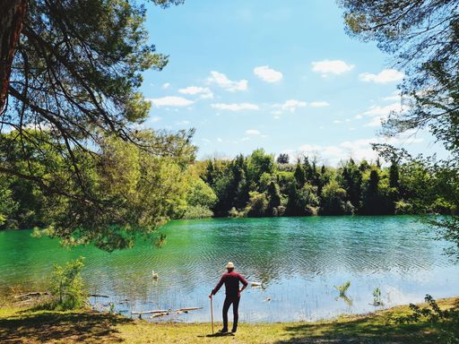 A back view of a hiker with a walking stick observing the beautiful Penne Lake in Abruzzo