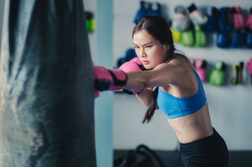 A female boxer hitting a punching bag with boxing gloves at the gym