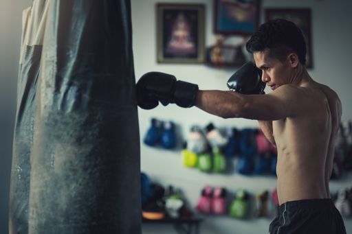 A male boxer hitting a punching bag with boxing gloves at the gym