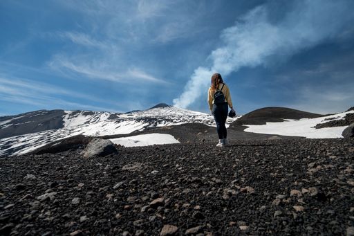 A beautiful shot of a girl walking on a snow covered path to the hills