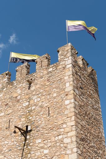 An old building with flags on top of it under a blue sky