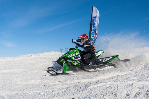 Snowmobile competing in extreme sports. Snowmobile jumps high above the track. On a snowmobile, a sportsman. It's a sunny day for a winter competition