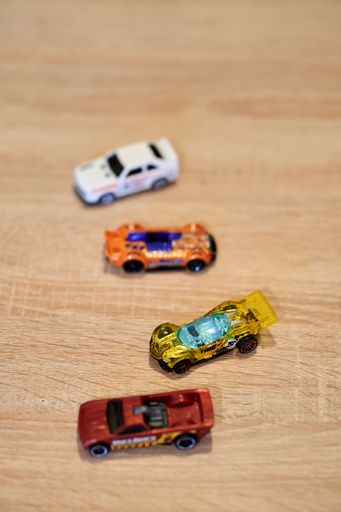 A vertical closeup of Mattel Hot Wheels toy model cars on a wooden surface.