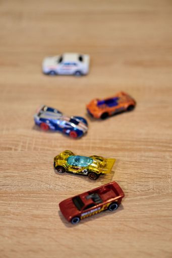A vertical closeup of Mattel Hot Wheels toy model cars on a wooden surface.