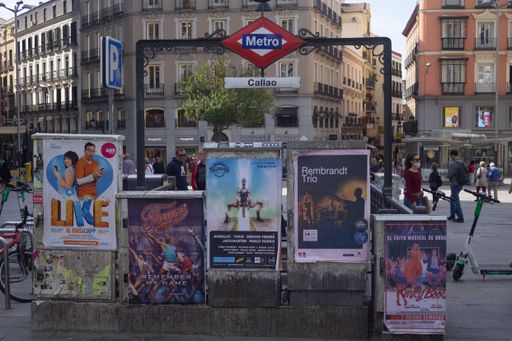 A Madrid metro station displays several advertising posters in Spain