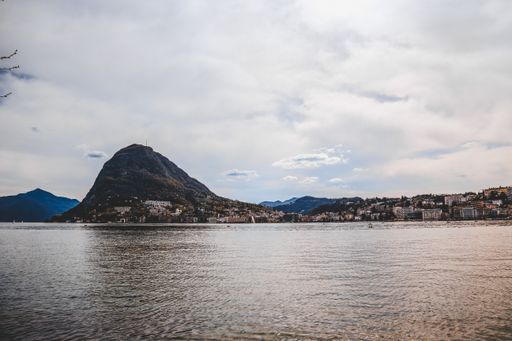 A horizontal shot of a lot of apartment buildings on the shore near the beautiful lake under the cloudy sky
