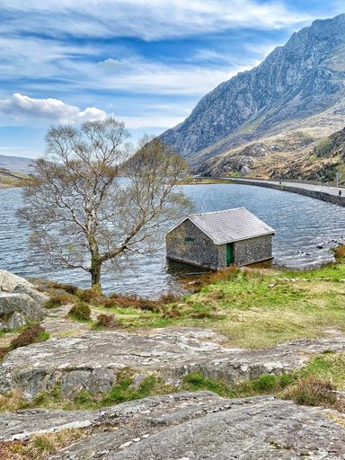 A vertical shot of a house on the shore of Llyn Ogwen lake in Wales