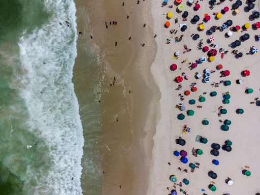 An aerial view of the beach and people swimming and relaxing