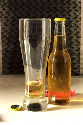 A vertical shot of a glass and a bottle of cold beer on a white table