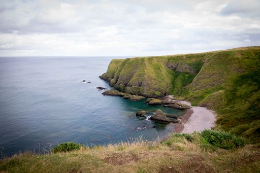 A high angle shot of the beautiful grass-covered cliffs by the ocean captured in Stonehaven, UK