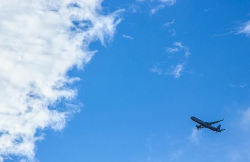 A flying airplane in a half cloudy skies
