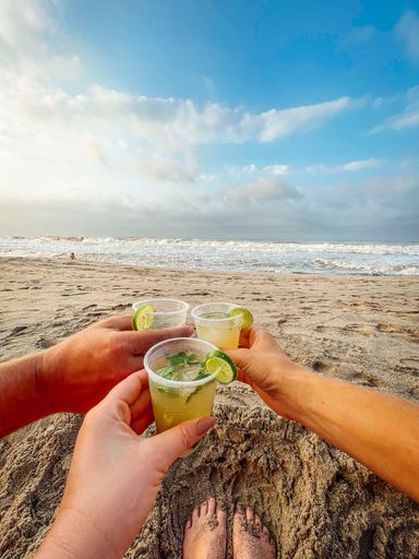 A closeup of friends holding a delicious cocktail at a beach under the sunlight