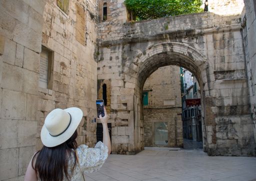 A young woman taking photos of the golden gates of Diocletian's Palace in Split, Croatia