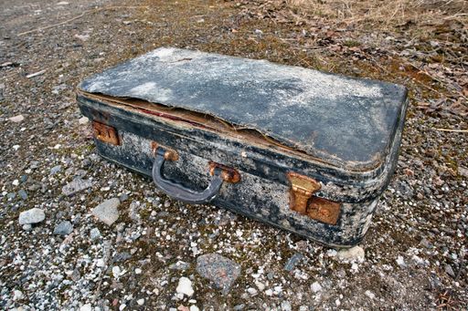 Old abandoned suitcase on ground outdoors