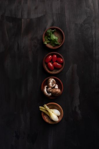 A vertical high-angle shot of some fresh vegetables in wooden bowls.