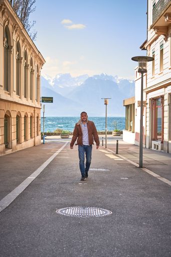 A vertical shot of a male walking in the street with Lake Geneva in the background, Montreux, Switzerland