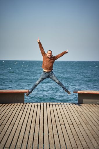 A vertical shot of a happy male jumping with Lake Geneva in the background in Montreux, Switzerland