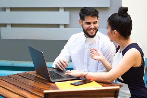A close up two people working on a laptop outdoors finance business