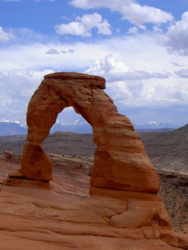 A vertical shot of the Delicate Arch against cloudy sky in the Arches National Park, Utah, USA