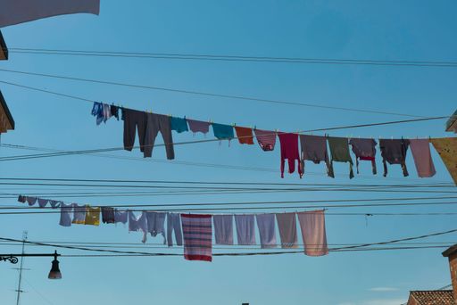 A low-angle shot of washed clothes drying on racks under the sunlight against a blue sky in Venice, Italy