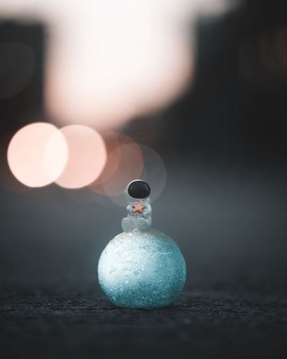 A vertical shot of an an astronaut figurine sitting on a lit moon isolated on a bokeh background