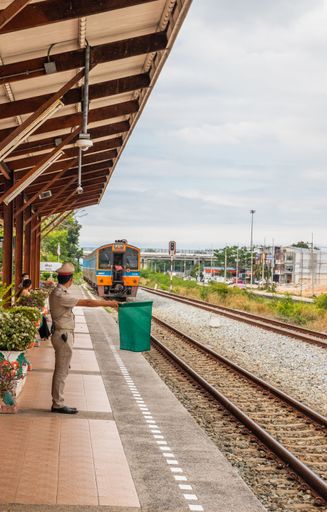 A train pulls into a station and waits for passengers in Thailand