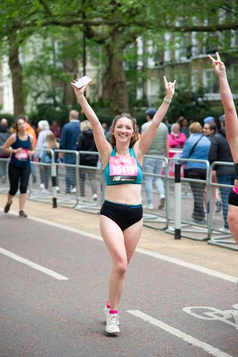 A vertical shot of a female runner  throwing her hands in the air during Vitality London 10000