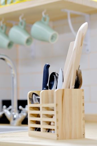 The  wooden organizer for kitchen utensils on the countertop in the kitchen, vertical