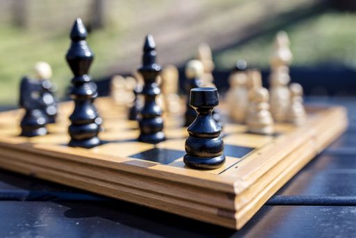 A closeup shot of the chessboard with chess pieces on blurred background under a sunlight