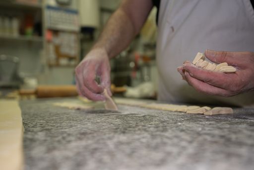 A baker cutting the dough into triangles for making croissants in a pastry shop