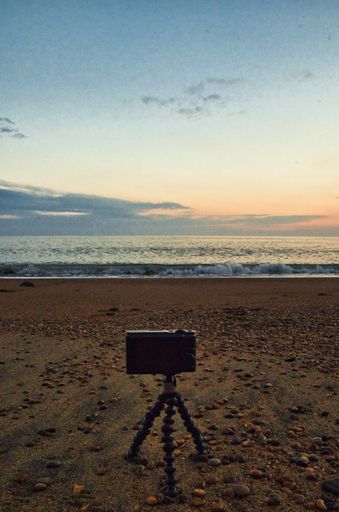 A mesmerizing view of a golden sunset over the sea with a tripod on the seashore